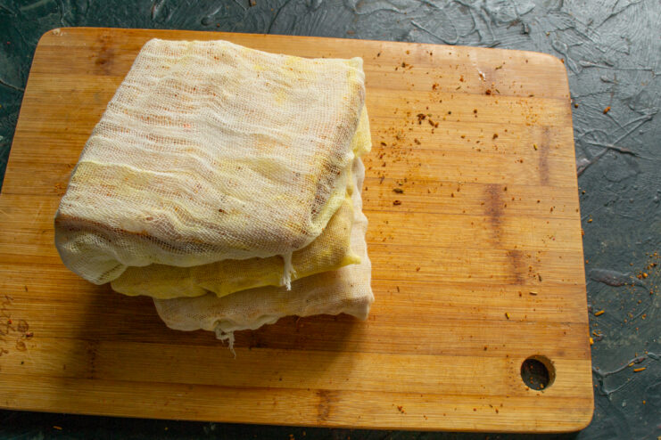 Wrapped salo Pork fat fully wrapped in several layers of white cheesecloth on a board