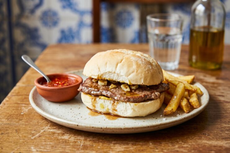Beef steak Prego sandwich with garlic sauce served alongside a portion of crispy french fries