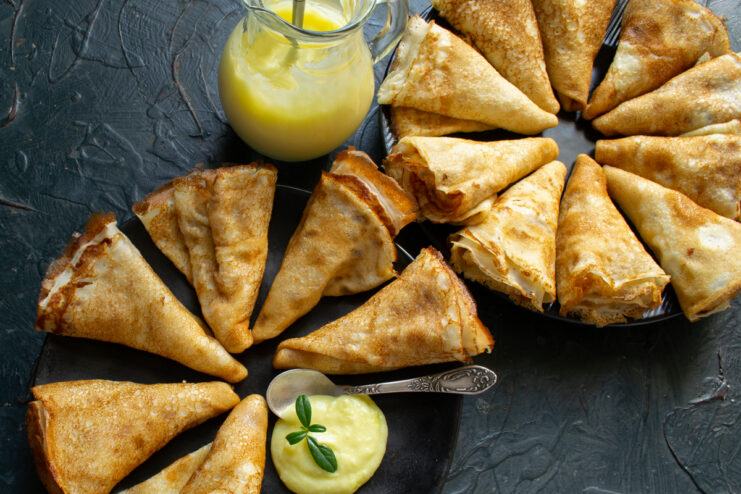 Cozy homemade crepes with vanilla sauce Arrangement of homemade crepes served with vanilla sauce on a table