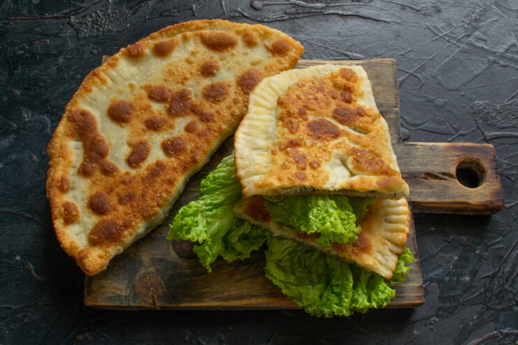 Serving the Dish Serving hot khachapuri with salad leaves on a wooden board