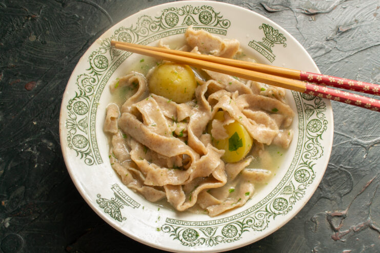 Plating the noodle soup Serving hot rye noodles and tender new potatoes topped with steaming broth
