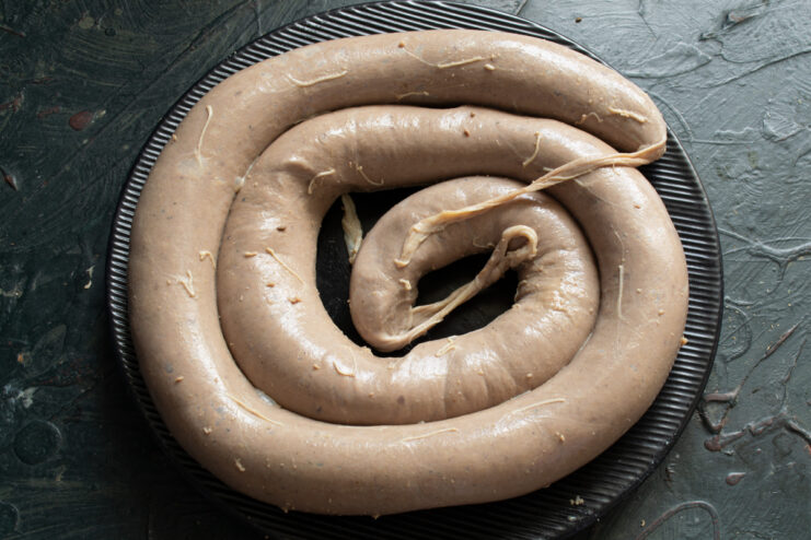 Stuffing The Sausage Raw stuffed sausage ring resting on a plate
