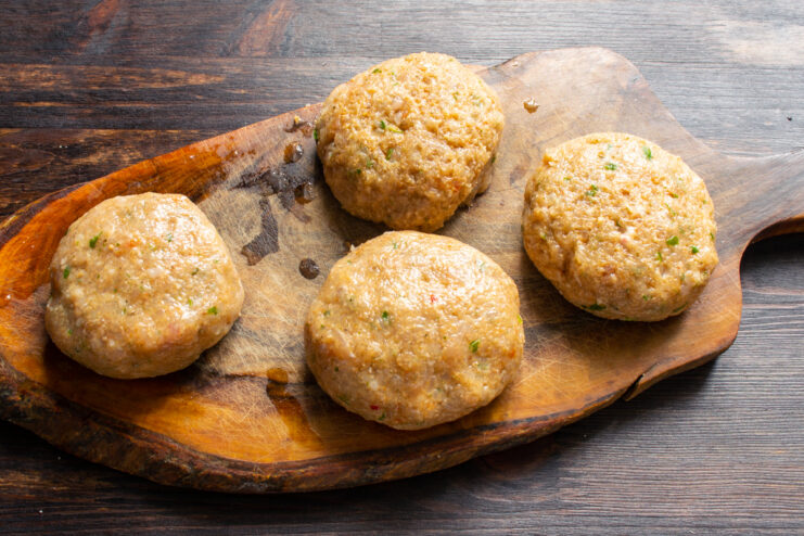 Shaping the patties Shaped round chicken patties resting on a wooden board