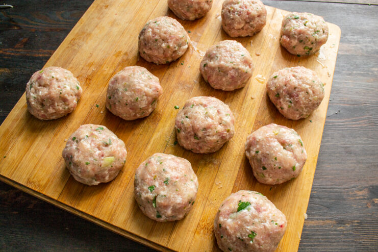 Forming The Meatballs Perfectly round, shaped meatballs arranged neatly on a wooden board.