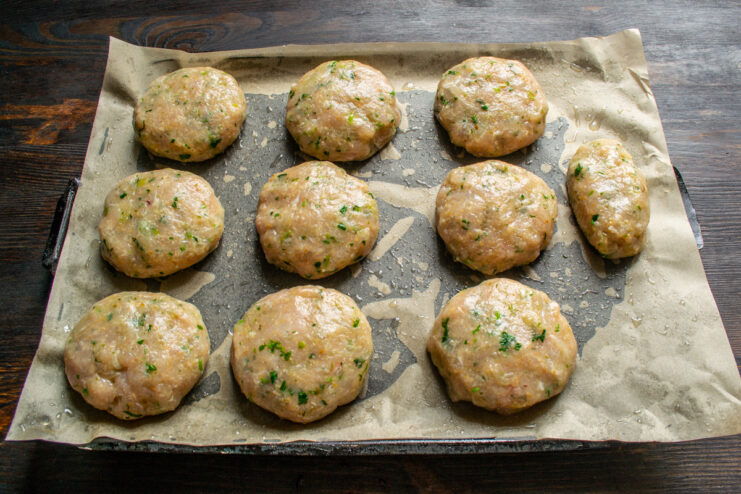 Shaping the patties Raw round chicken patties arranged on a parchment-lined baking sheet