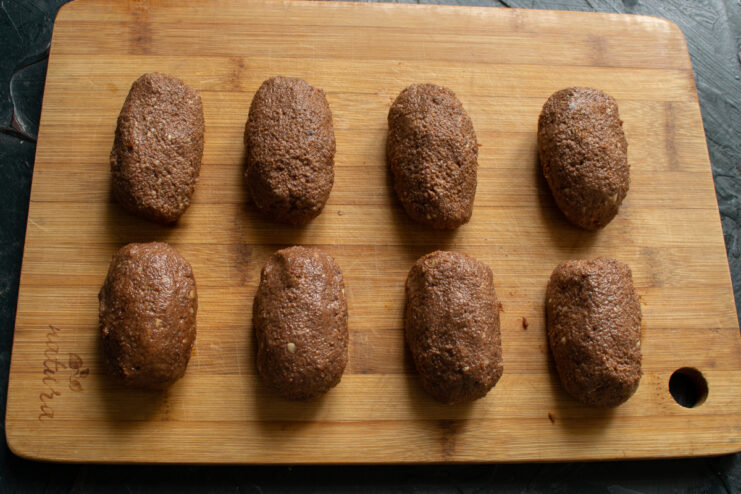 Shaped Nochka pastries on a wooden cutting board.