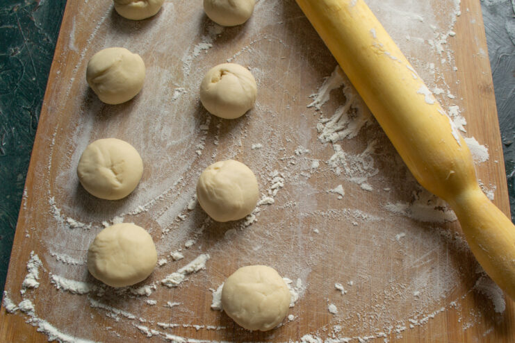 Smooth dough balls arranged on a flour-dusted board