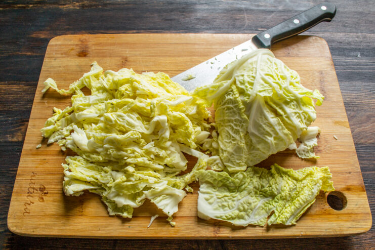 Shredding the cabbage Shredding fresh Savoy cabbage on a wooden cutting board