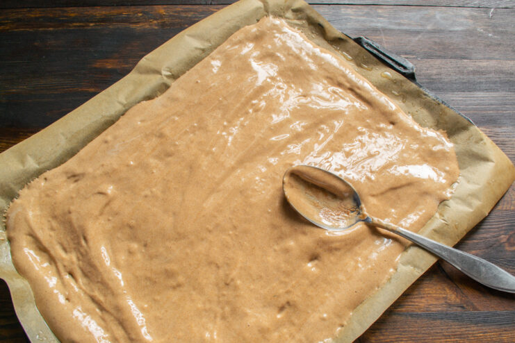Spreading the batter on the baking sheet Spreading a thin layer of chocolate batter on a parchment-lined baking sheet.