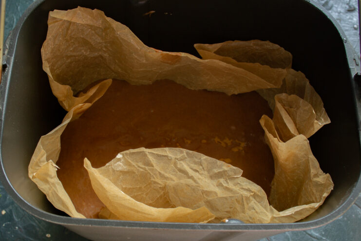 Prepping for baking Pouring chocolate batter into a parchment-lined bread maker pan