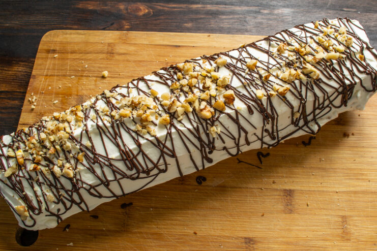 Decorating with chocolate and nuts Decorating the frosted chocolate roll with melted chocolate drizzles and chopped walnuts.