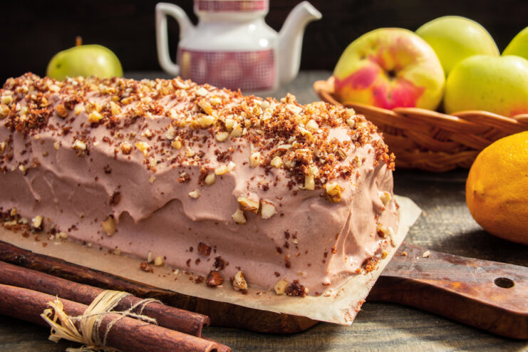 Finished chocolate and apple cake topped with chopped nuts on a wooden board