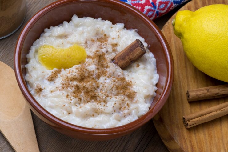 Creamy Arroz Doce rice pudding garnished with intricate cinnamon patterns and lemon