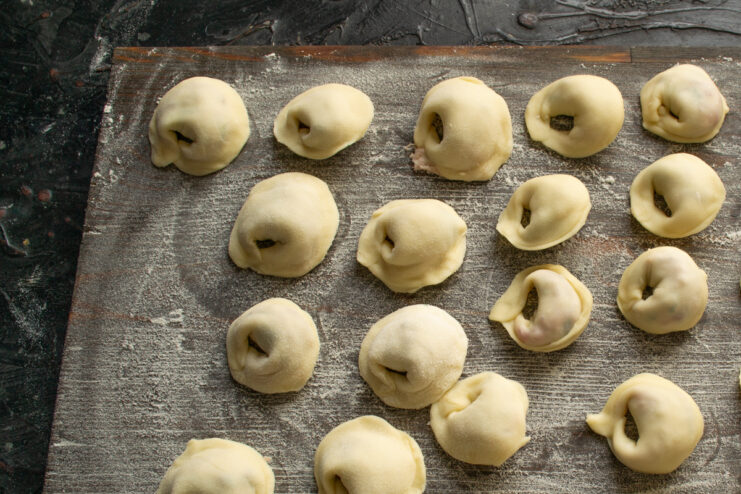 Shaped homemade dumplings on a wooden cutting board