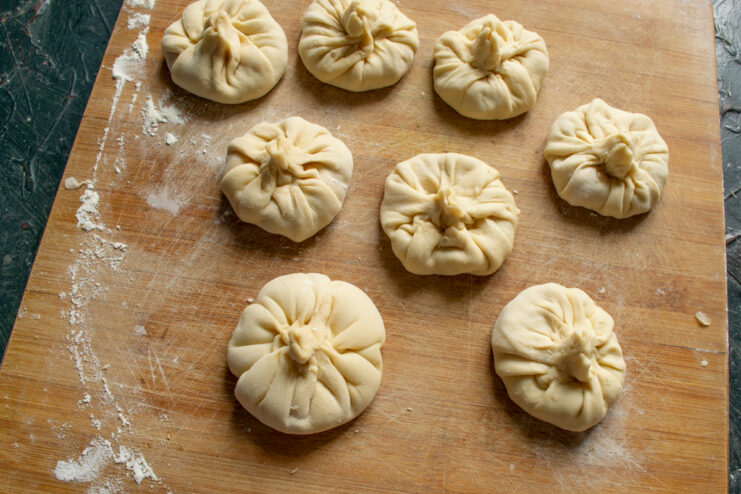 Freshly shaped khinkali resting on a wooden surface