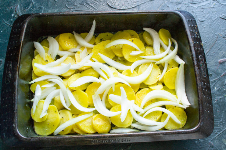 Layering thin onion wedges over pre-baked sliced potatoes