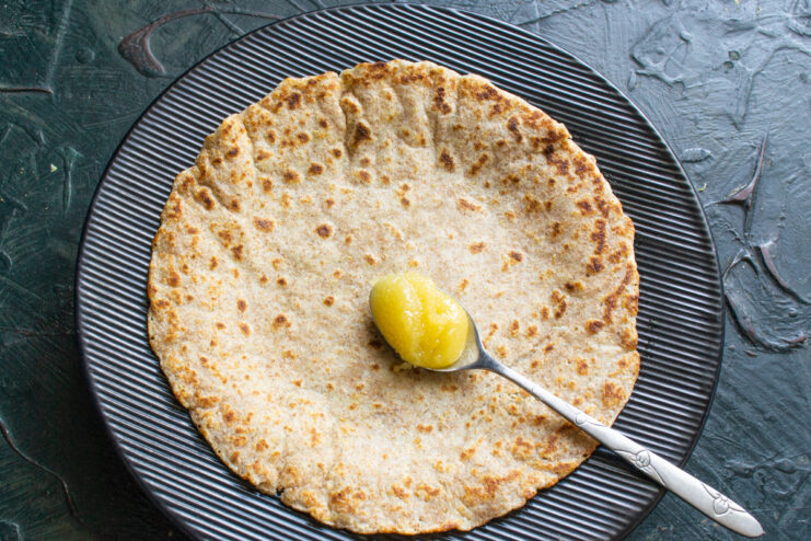 Adding honey to the hot crepe Spreading honey over a freshly cooked hot crepe