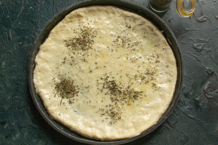 Aromatic pizza base Brushing the dough with olive oil and sprinkling spices