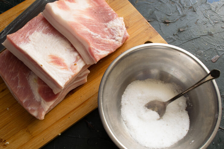 Curing mixture Mixing coarse salt and sugar in a metal bowl next to the pork fat