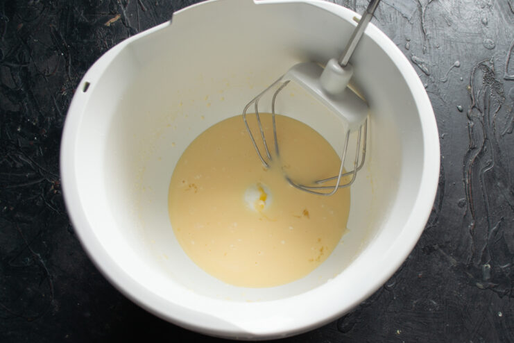 Blending liquid ingredients Whisked liquid dough ingredients in a white ceramic mixing bowl.