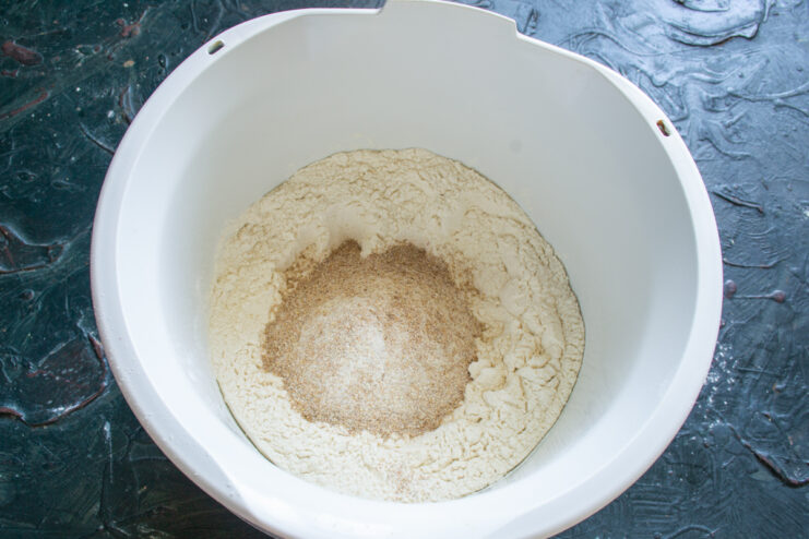Dry Ingredients For Bread Mixing two types of flour, salt, and sugar in a white mixing bowl.