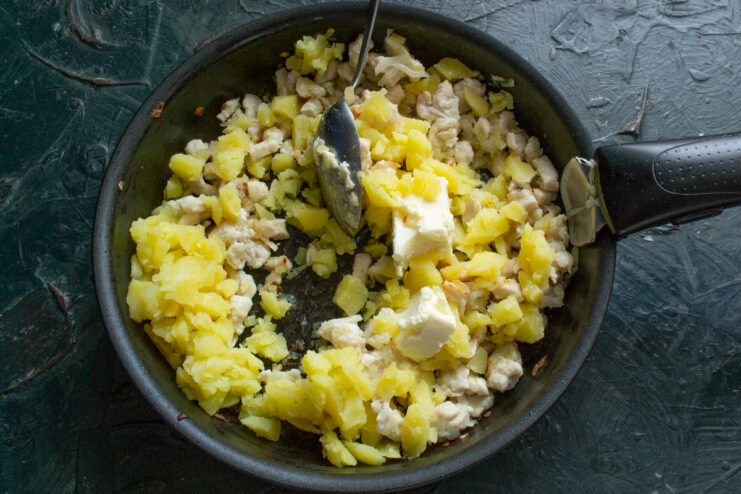 Mixing the filling Mixing chicken, mashed potatoes, and butter in a skillet