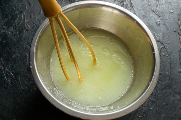 Whisking liquid ingredients for crepe batter Whisking milk water and oil in a bowl until dissolved