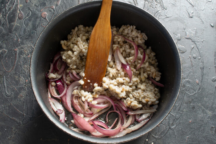 Combining the ingredients Stirring cooked pearl barley into sautéed shallots
