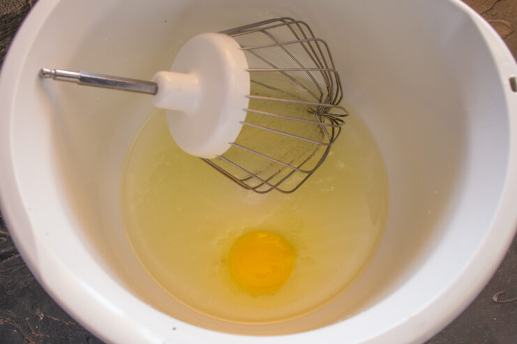 Preparing the wet ingredients Whisking the egg, oil, and milk in a mixing bowl for the dough