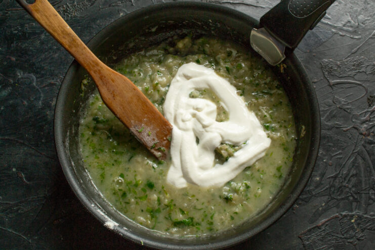 Adding sour cream to sauce Sour cream stirred into a savory sauce in a skillet