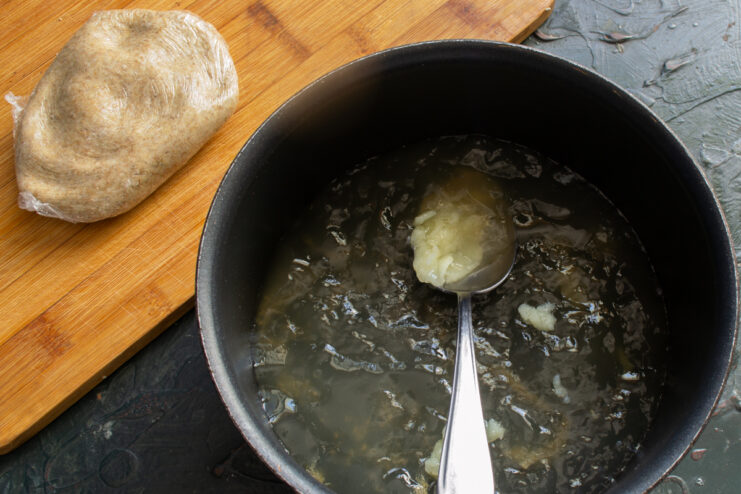 Skimming fat from the broth Carefully skimming solidified fat from the surface of chilled chicken broth