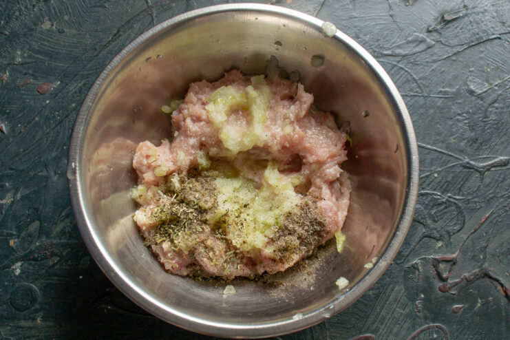 Spices for homemade patties Salt, pepper, and Herbes de Provence on top of the minced meat