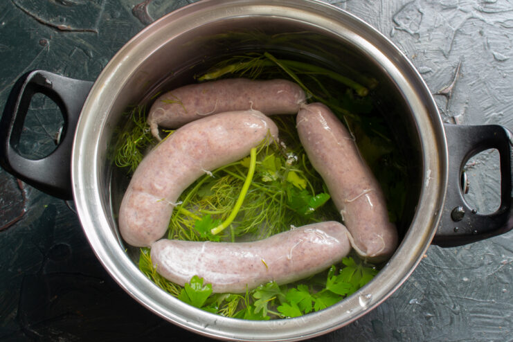 Prepping to boil Sausages in a pot of water with fresh herbs