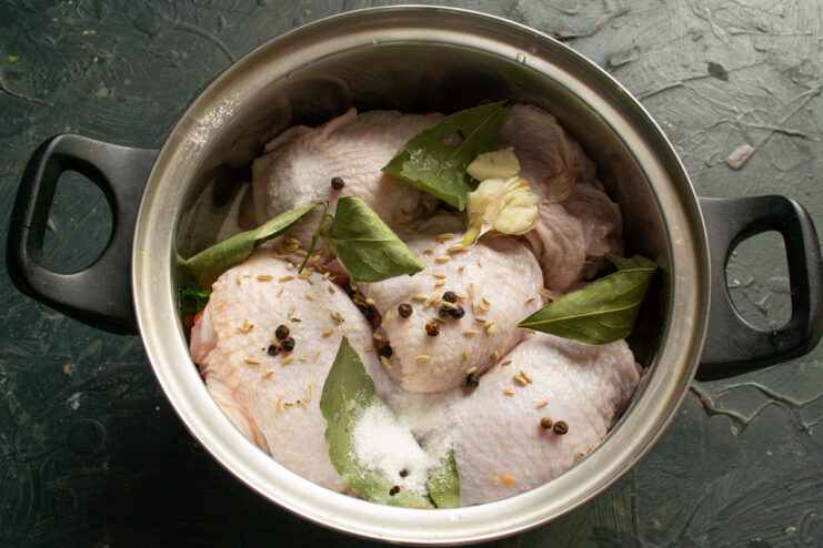 Adding the spices Spices, bay leaves, and crushed garlic added over the chicken