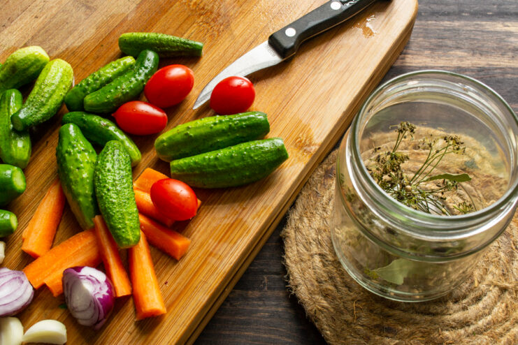 Spices, dill, and a bay leaf at the bottom of a glass jar