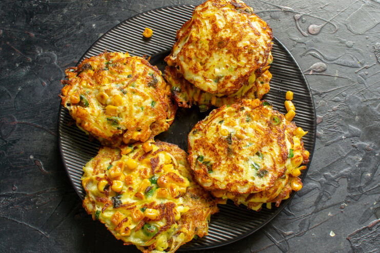 Serving hot fritters with sauce Stack of golden potato fritters on a dark serving plate