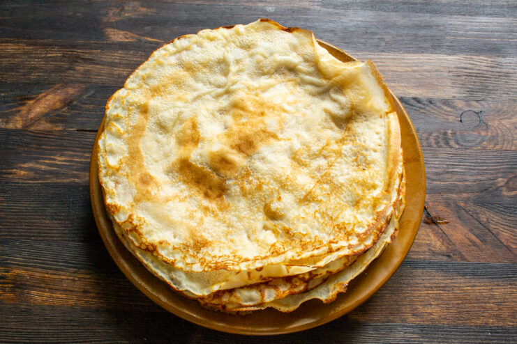 Stacking cooked crepes Stack of freshly cooked golden crepes on a plate