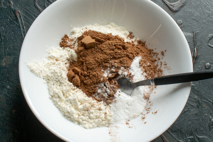 Preparing the dry ingredients Whisking dry ingredients for chocolate sponge cake in a white bowl