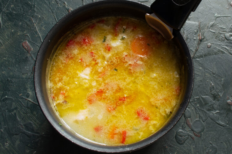 Adding the heavy cream Cod soup in a pot being stirred after adding heavy cream
