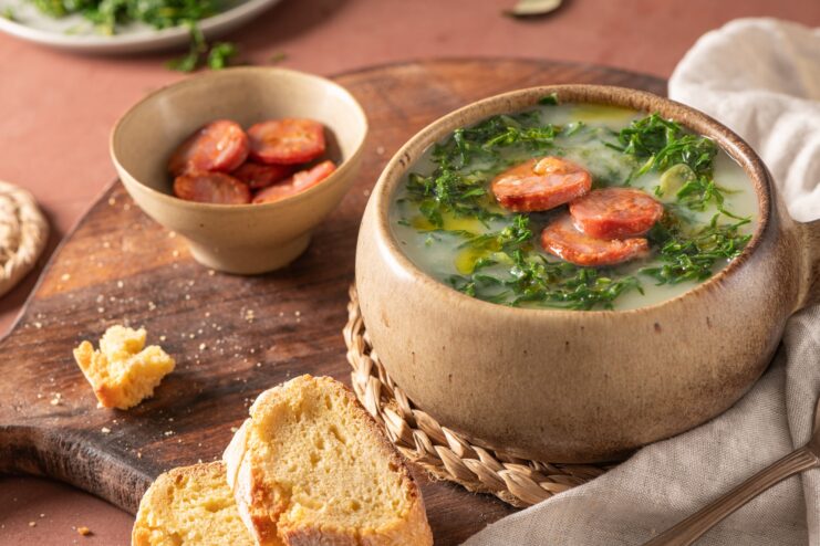 Traditional Caldo Verde soup served in a rustic clay bowl topped with a slice of chouriço