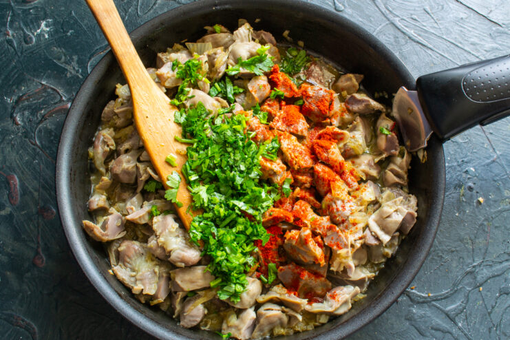 Adding herbs and spices Fresh cilantro and red pepper on top of gizzards