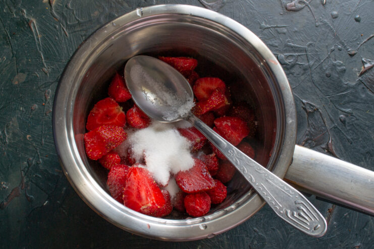Preparing the strawberry base Fresh chopped strawberries and sugar simmering in a saucepan