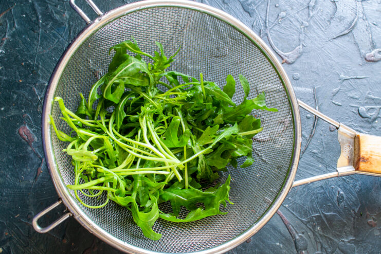 Preparing the greens Fresh arugula leaves draining in a metal colander