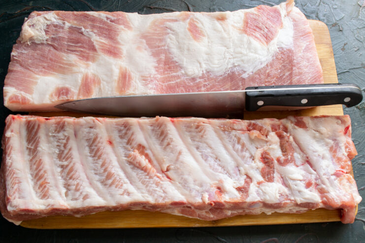 Selecting the meat Fresh raw pork belly with ribs attached lying on a wooden cutting board