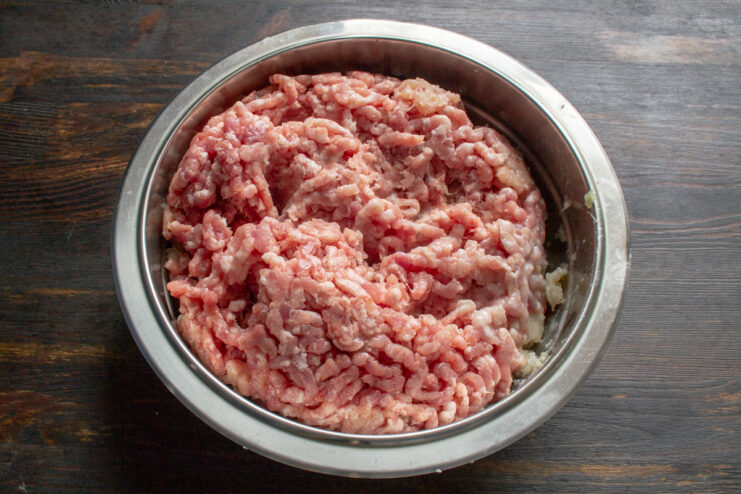 Grinding The Meat Freshly ground meat mixture sitting in a stainless steel bowl after being processed.