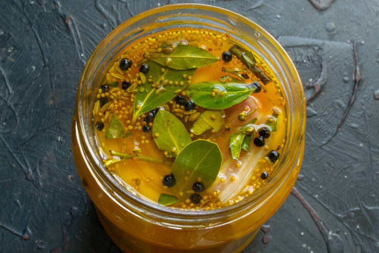 Curing Pork Belly in Brine Pork belly submerged in a golden turmeric brine with peppercorns inside a glass jar