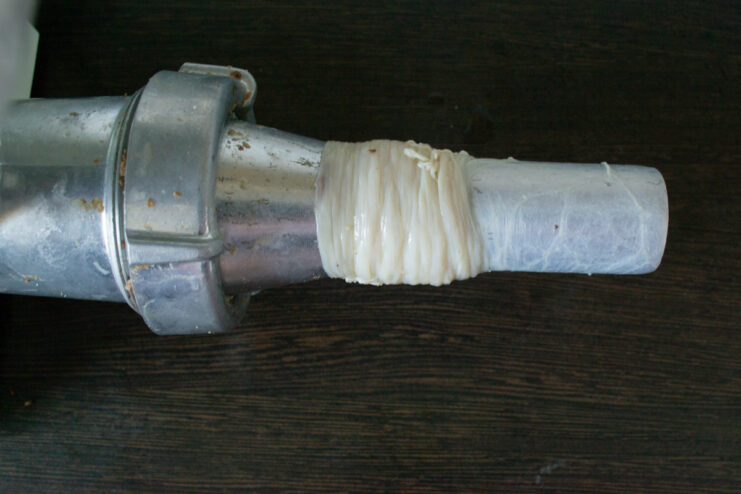 Assembling The Meat Grinder Pork casing threaded onto a sausage stuffer attachment