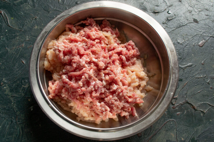 Making the mixed meat mince Ground pork being added to the bowl with ground chicken
