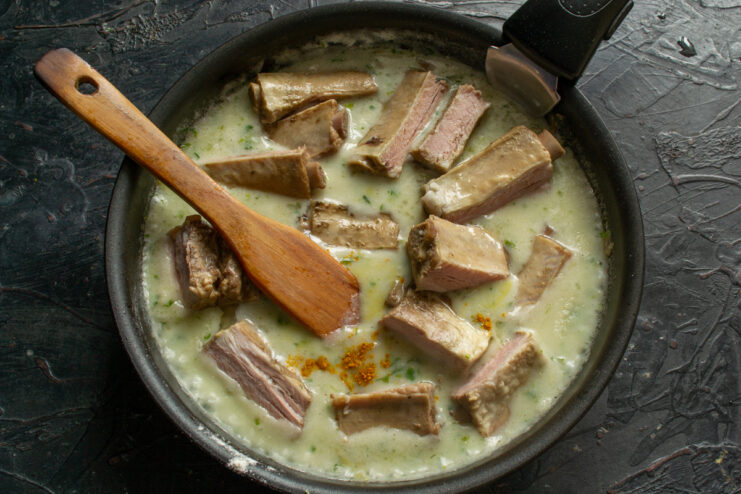 Adding ribs to the sauce Boiled pork ribs simmering in a creamy sauce