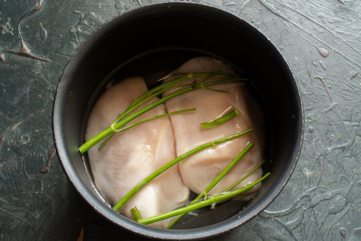 Preparing chicken for pate Raw chicken breast in a pot of water with fresh dill sprigs and spices